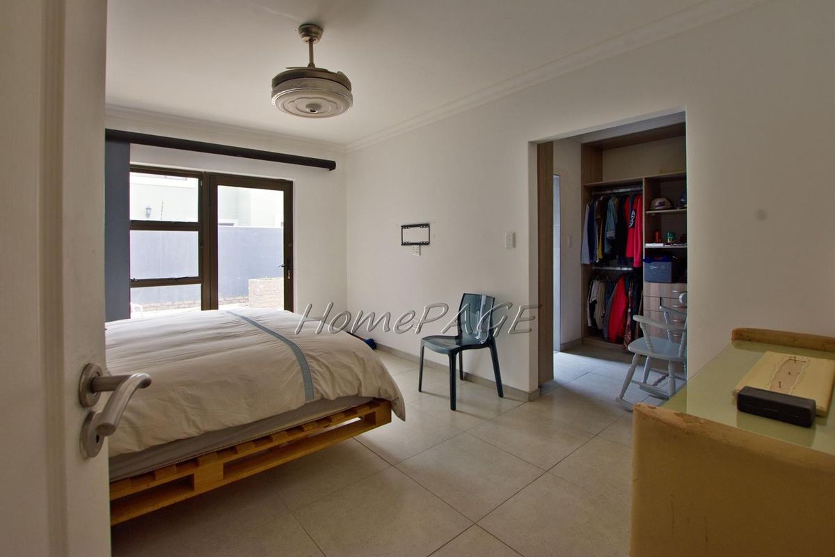 A bedroom featuring tiled flooring, a ceiling fan, and an integrated walk-in closet with built-in shelving.