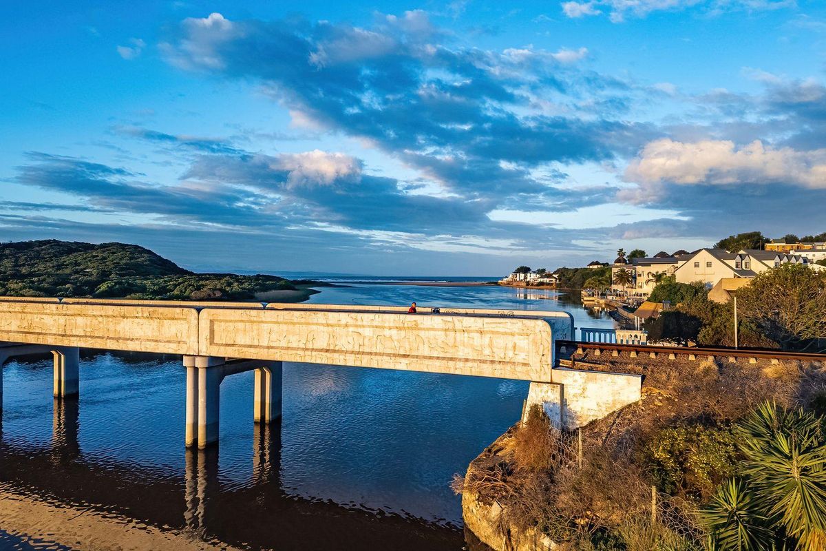 Aerial view of the coastal landscape featuring a concrete bridge spanning the river with residential properties visible in the background.