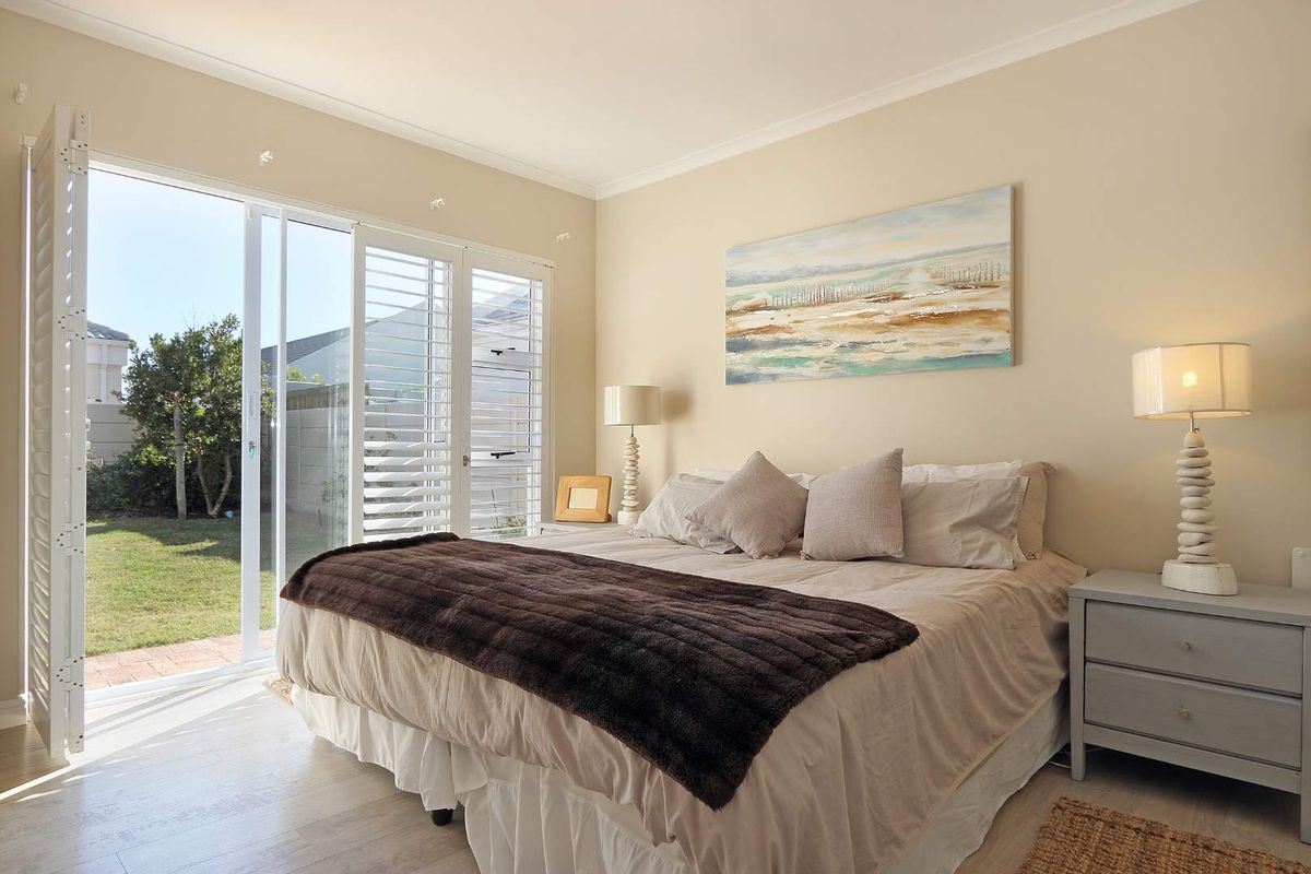 Bright bedroom featuring laminate flooring, plantation shutters, and sliding glass doors providing direct access to the rear garden.