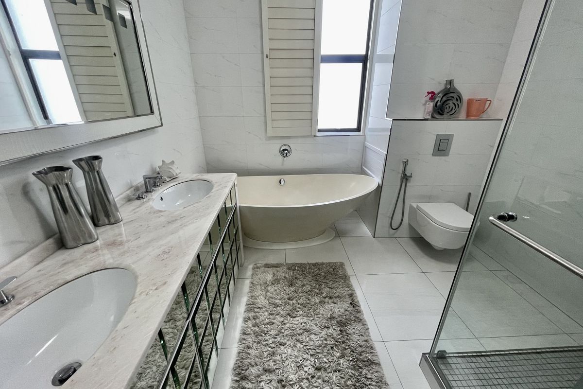 Modern bathroom featuring a double vanity with marble countertop, a sleek freestanding bathtub, wall-mounted toilet, and a separate glass-enclosed shower.