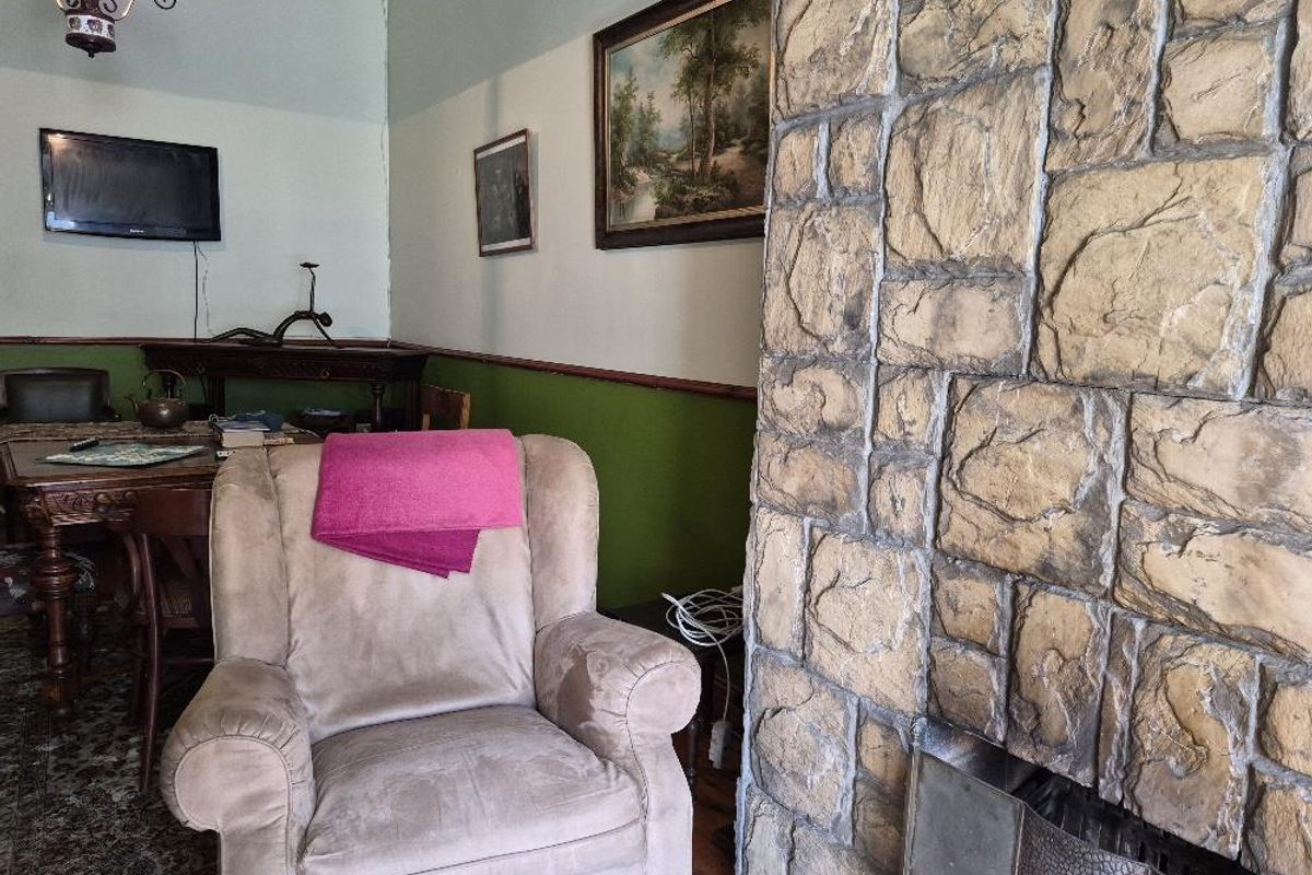 Living room featuring a prominent stone fireplace, chair rail molding, and two-tone wall paint, offering a traditional aesthetic with potential for modernization.