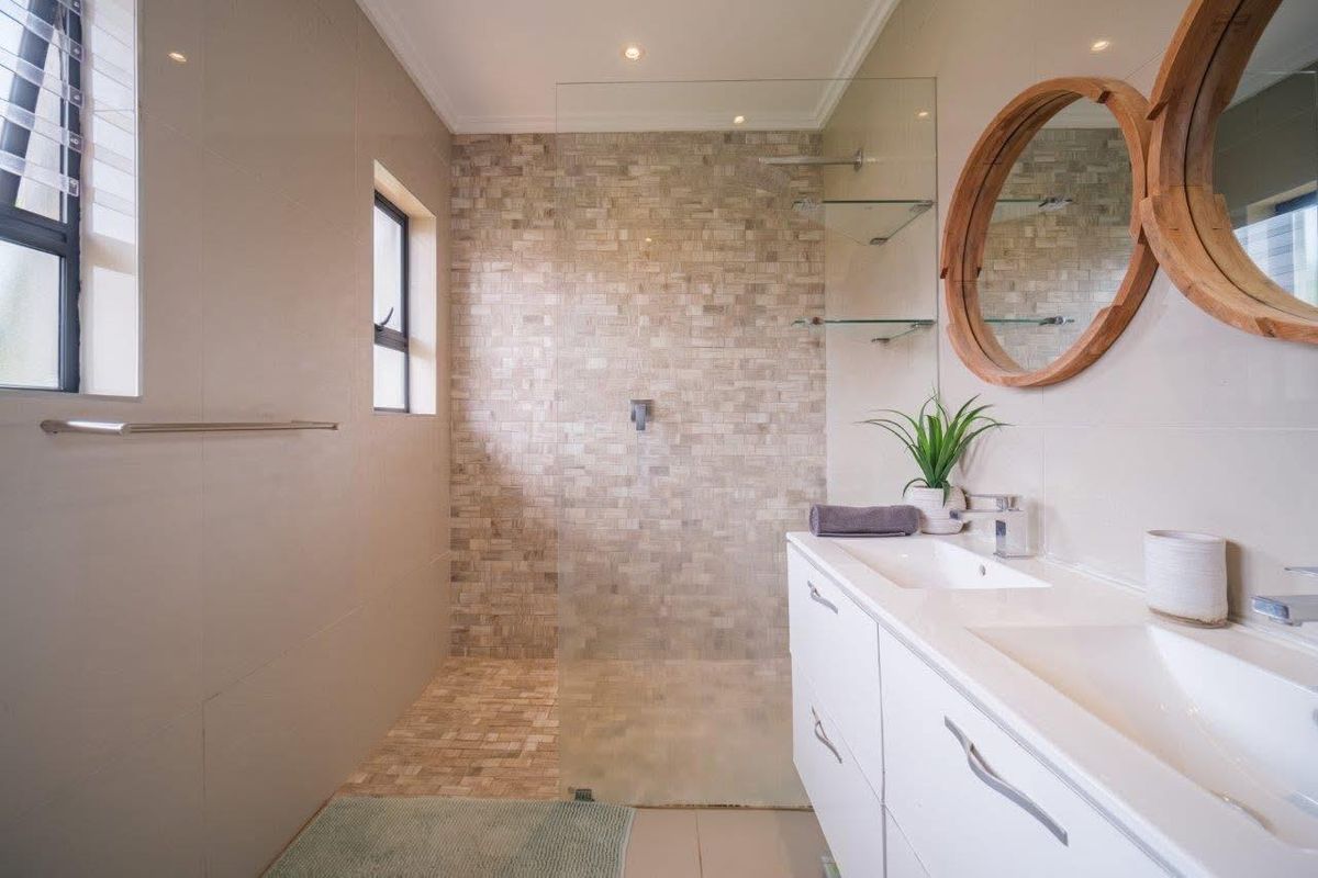 Modern bathroom featuring a walk-in shower with mosaic tile accents, a double vanity with integrated sinks, and contemporary fixtures.