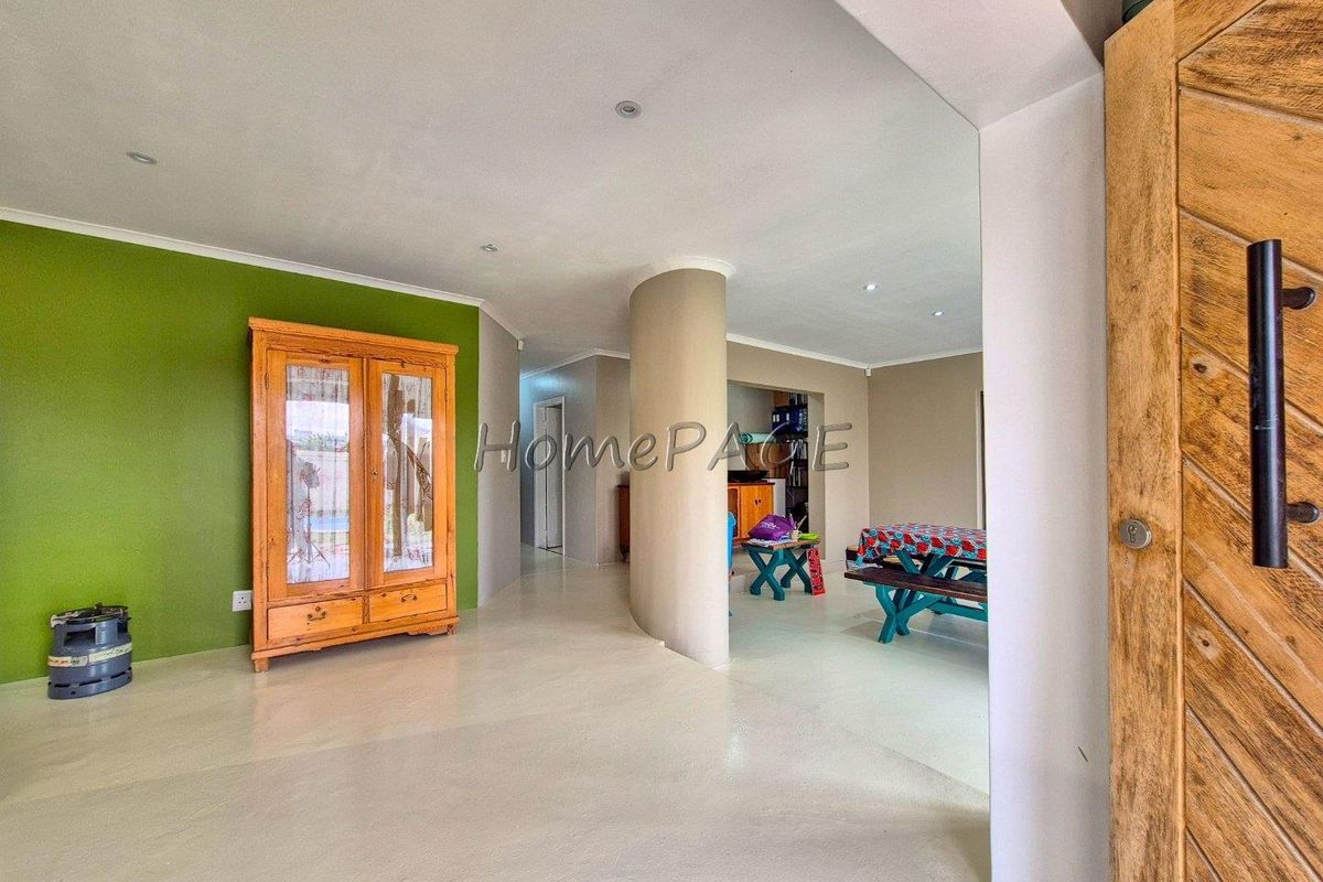 Spacious living area featuring polished concrete floors, a distinctive curved structural column, and recessed downlighting, leading into an open-plan layout.