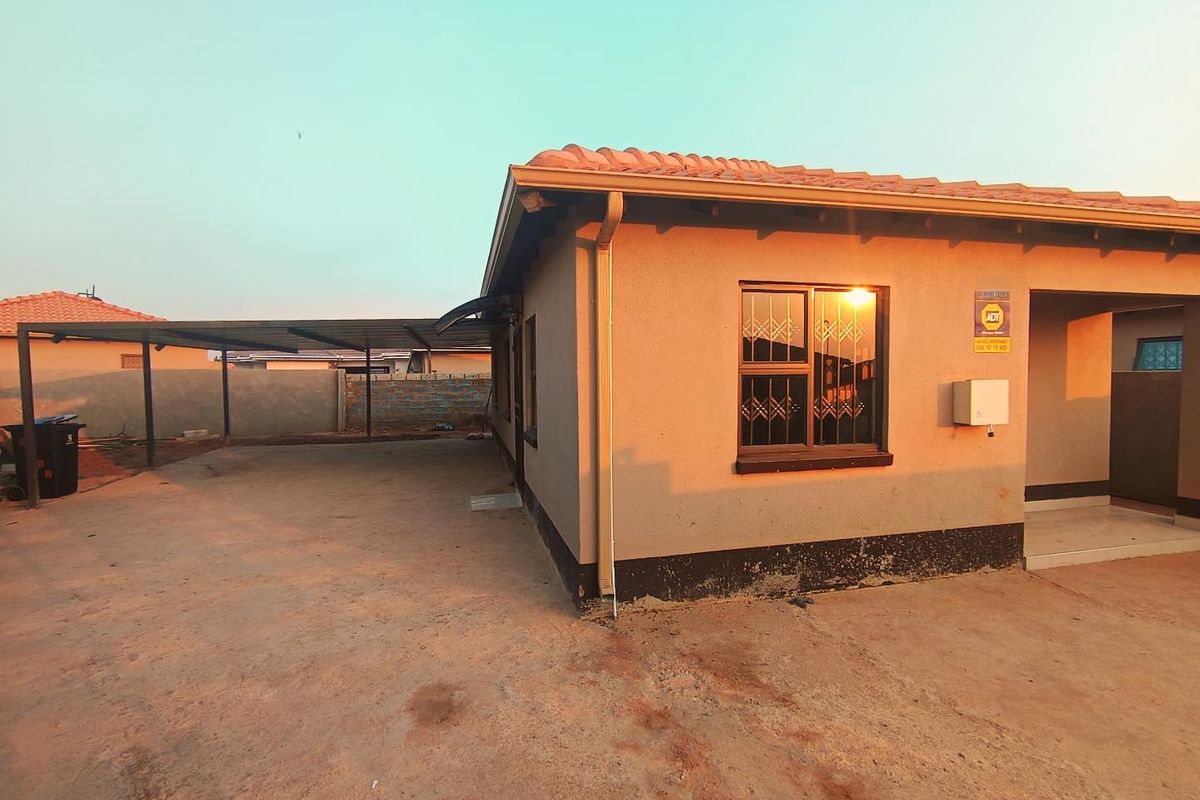 Rear exterior view of the house featuring a covered carport, concrete driveway, and security bars on the windows.