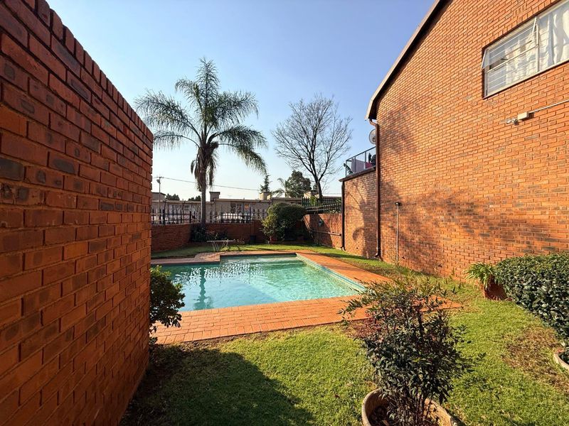Private outdoor area featuring a swimming pool surrounded by brick paving and enclosed by a brick boundary wall.