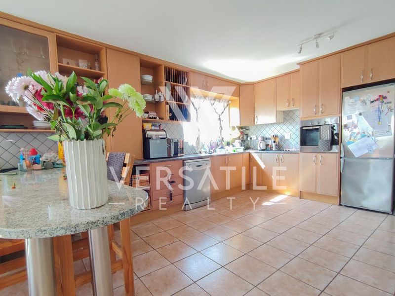 A functional kitchen featuring light wood cabinetry, granite countertops, a breakfast bar, and tiled flooring with a built-in oven.