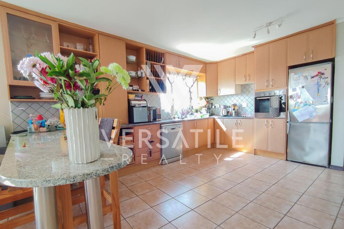 A functional kitchen featuring light wood cabinetry, granite countertops, a breakfast bar, and tiled flooring with a built-in oven.
