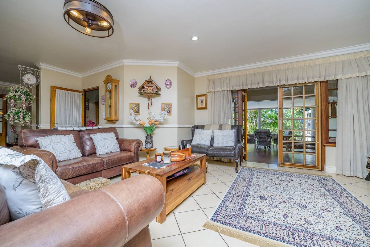 Spacious living room featuring tiled flooring, crown molding, and French doors providing seamless access to the outdoor patio area.