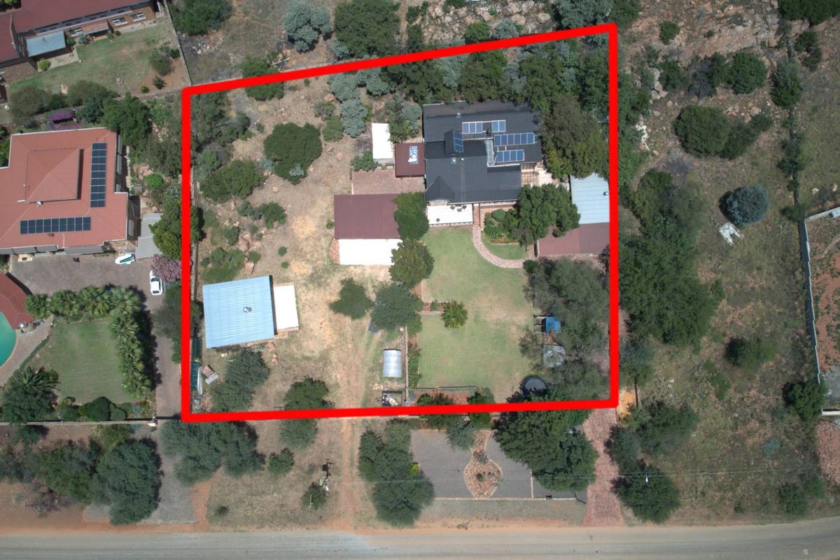 Aerial view of the property showing the main dwelling, outbuildings, landscaped garden, and surrounding grounds within the highlighted boundary.