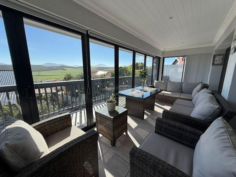 A bright, enclosed patio featuring large sliding glass doors, modern tiled flooring, and a tongue and groove ceiling with recessed lighting, offering scenic views.