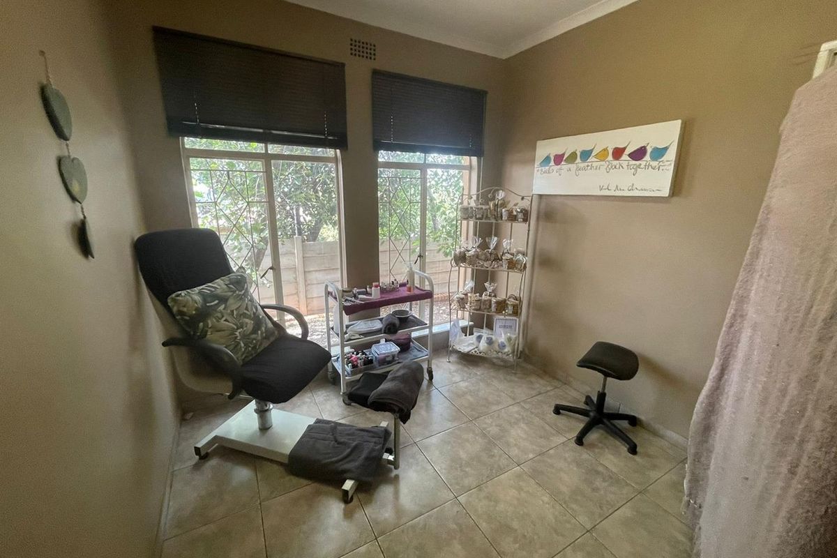 A functional room featuring tiled flooring and large windows with security bars, currently utilized as a beauty treatment space.