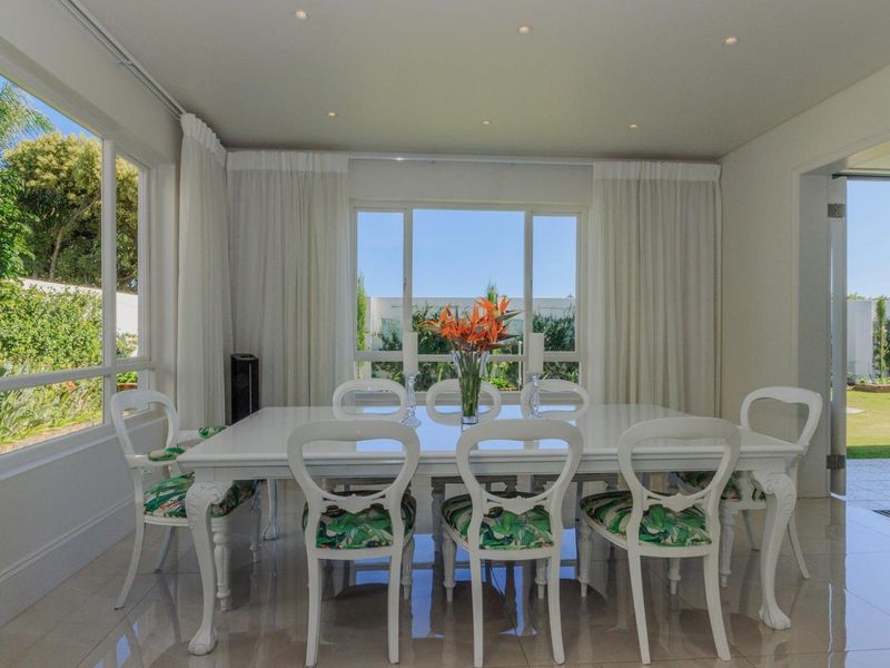Bright and spacious dining room featuring large windows, recessed lighting, and polished floor tiles with direct access to the outdoor patio and garden.