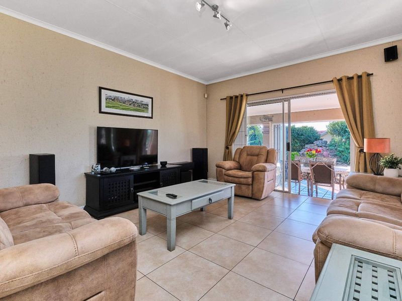 Spacious living room featuring neutral tiled flooring and large sliding glass doors that provide seamless access to the outdoor patio area.