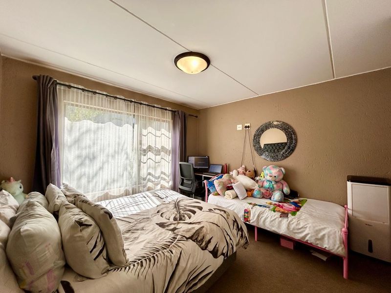 A functional bedroom featuring carpeted flooring, a ceiling light fixture, and a large sliding glass door providing natural light.