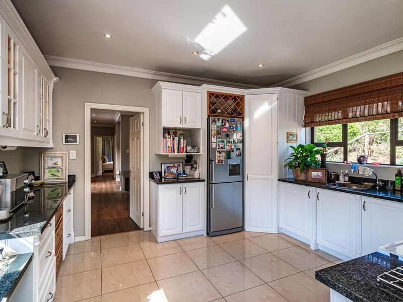 A well-maintained kitchen featuring white cabinetry, granite countertops, ceramic tile flooring, and recessed lighting, offering a clean and functional workspace.