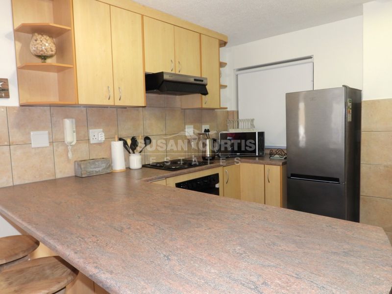 A functional kitchen featuring laminate countertops, tiled backsplash, built-in cabinetry, and integrated cooking appliances including a hob and extractor fan.
