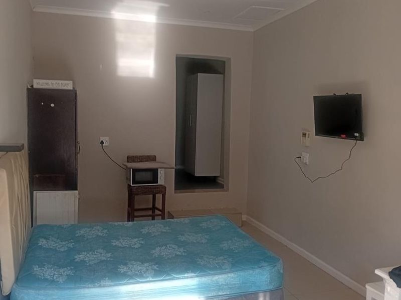 A functional bedroom featuring tiled flooring, a ceiling fan, and a built-in cupboard, providing a simple and practical living space.