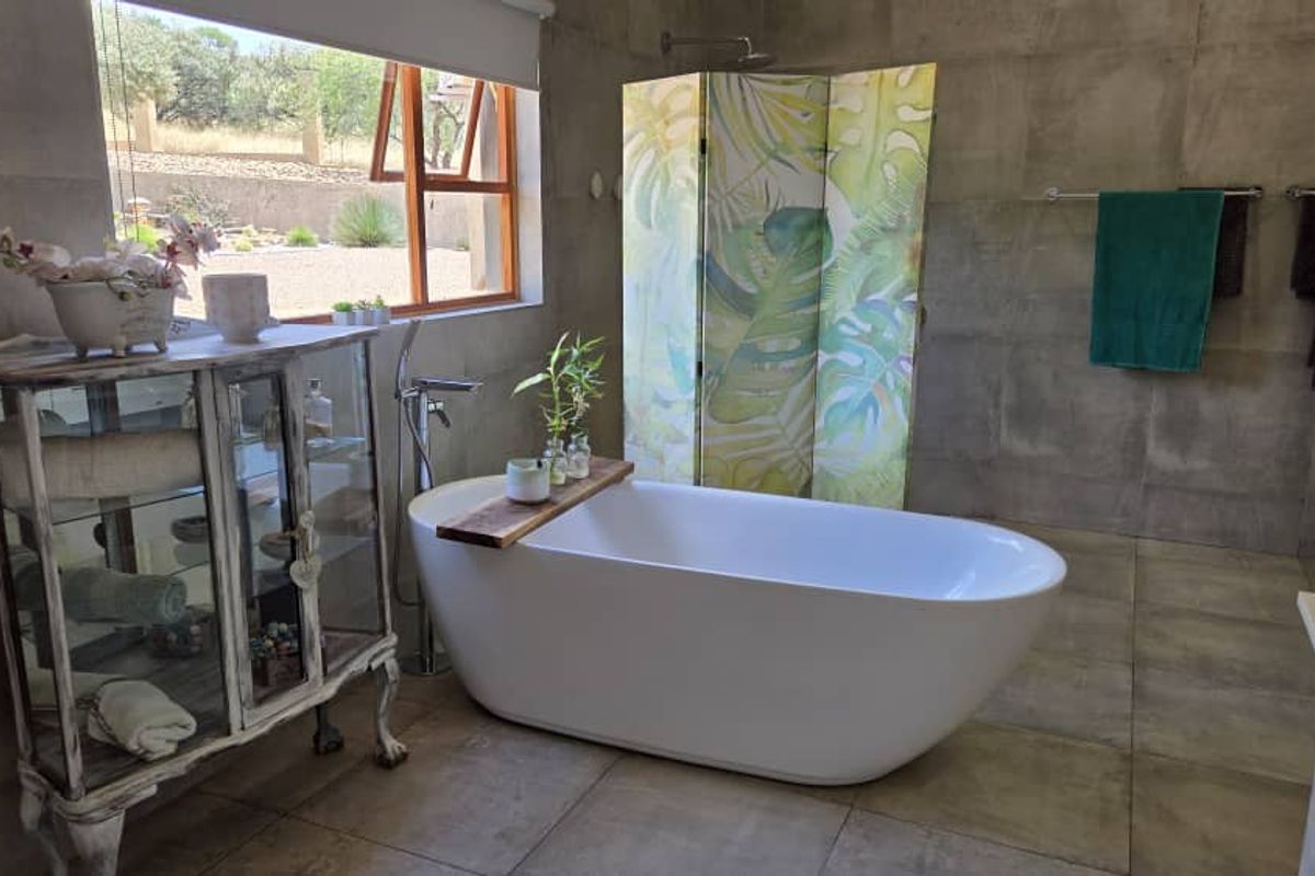 Modern bathroom featuring a freestanding soaking tub, large format wall and floor tiles, and a window with natural light.