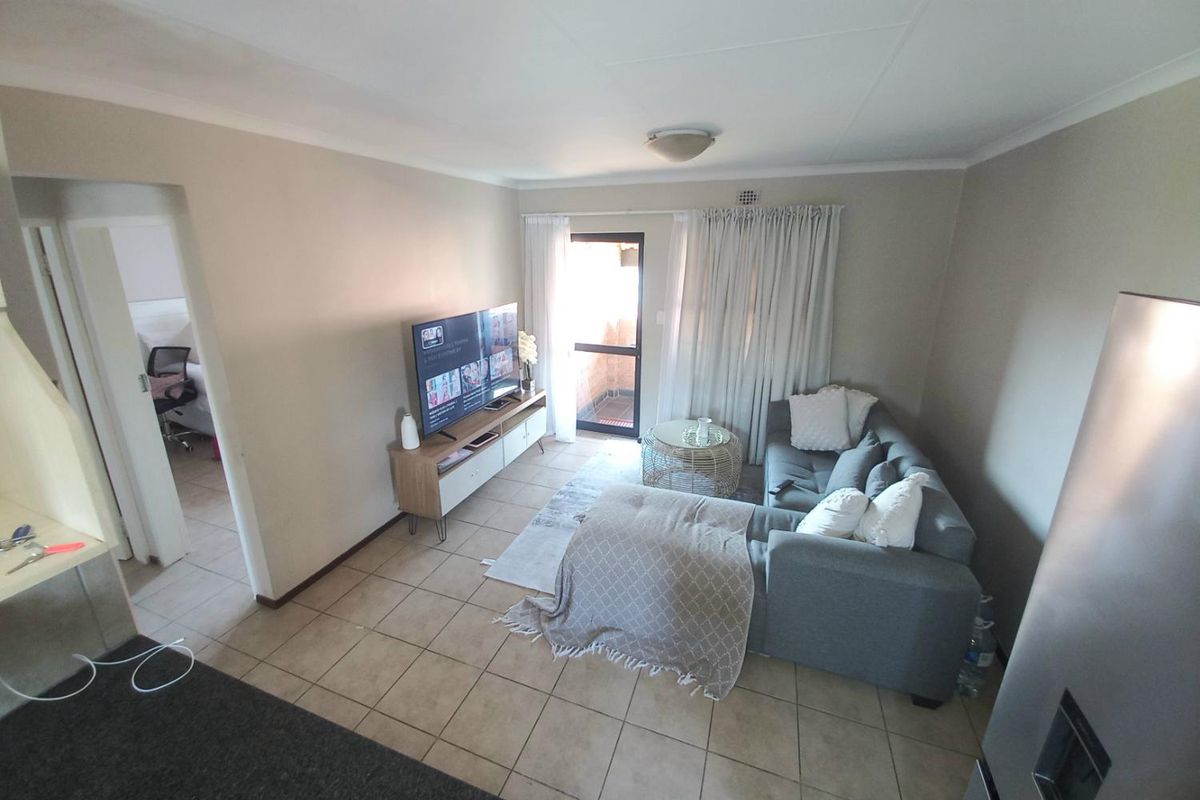 A functional living room featuring tiled flooring and direct access to an outdoor balcony area through a glass door.