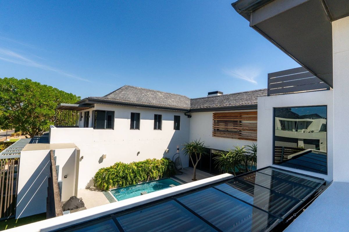 Elevated view of a modern residential property featuring a private swimming pool, landscaped garden area, and contemporary architectural design with clean lines.