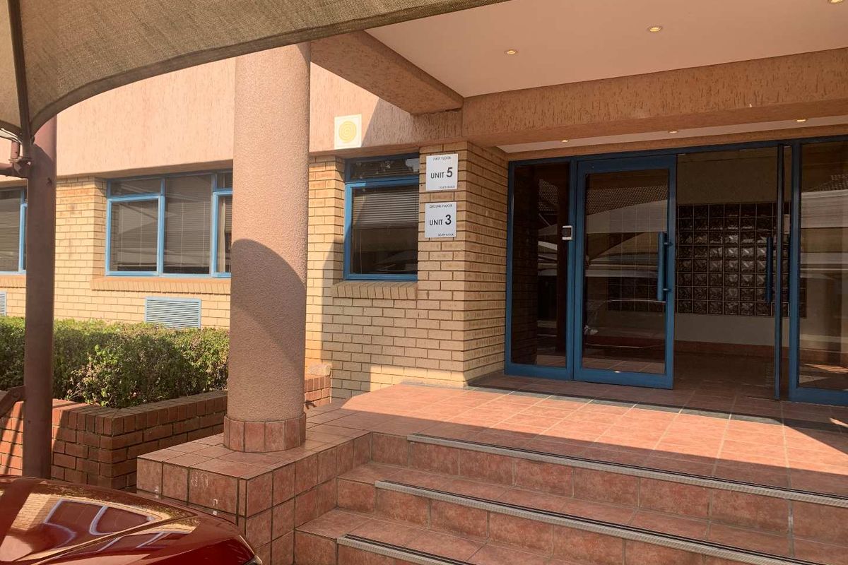 Main entrance to the office building featuring a tiled porch, brick facade, glass double doors, and integrated mailboxes.