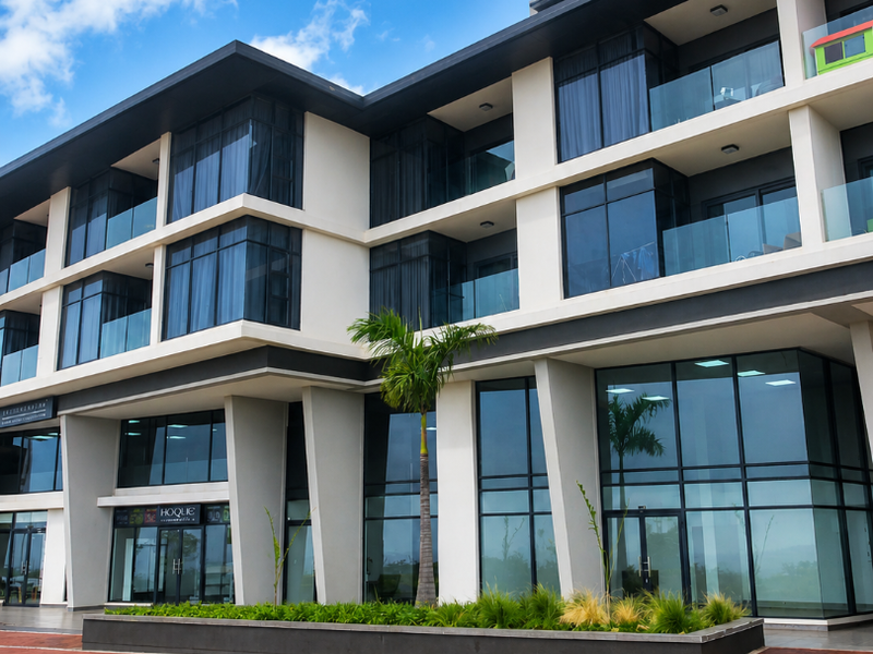 Modern multi-story retail and residential building featuring extensive glass facades, private balconies, and a clean, contemporary architectural design.