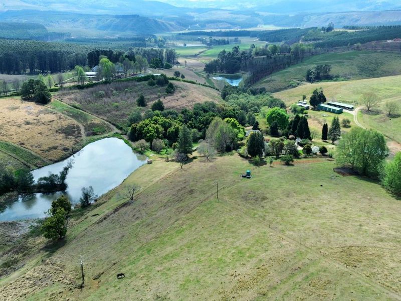 An expansive aerial view of the farm property, showcasing rolling hills, natural landscape, and a private dam.