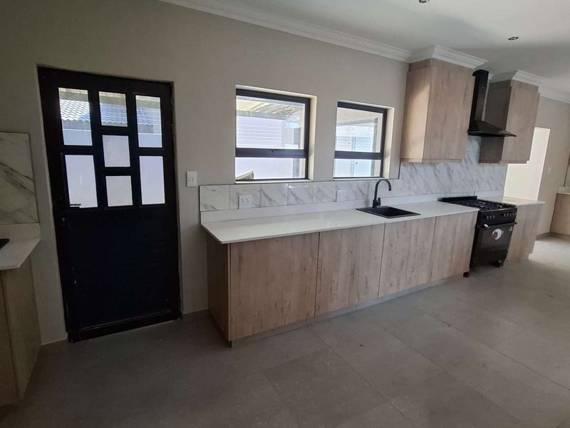 Modern kitchen featuring light wood-grain cabinetry, stone countertops, marble-look backsplash, and integrated gas stove with extractor fan.