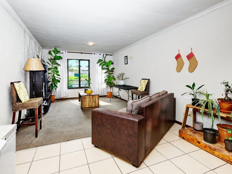 Open plan living area featuring a combination of tiled and carpeted flooring with natural light from a window.