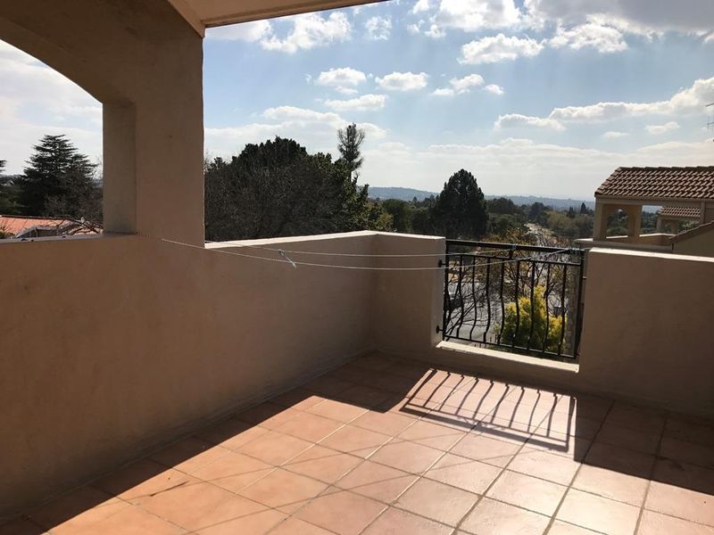 A spacious covered balcony featuring tiled flooring and a wrought iron balustrade, offering elevated views of the surrounding area.