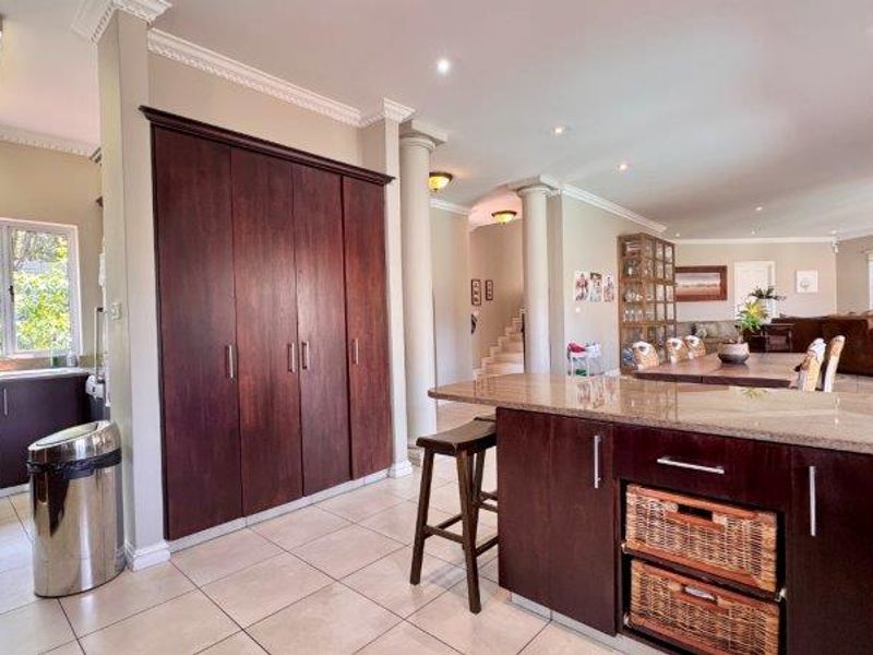 Spacious open-plan living area featuring a kitchen with granite countertops, dark wood cabinetry, and seamless flow into the dining and lounge spaces.