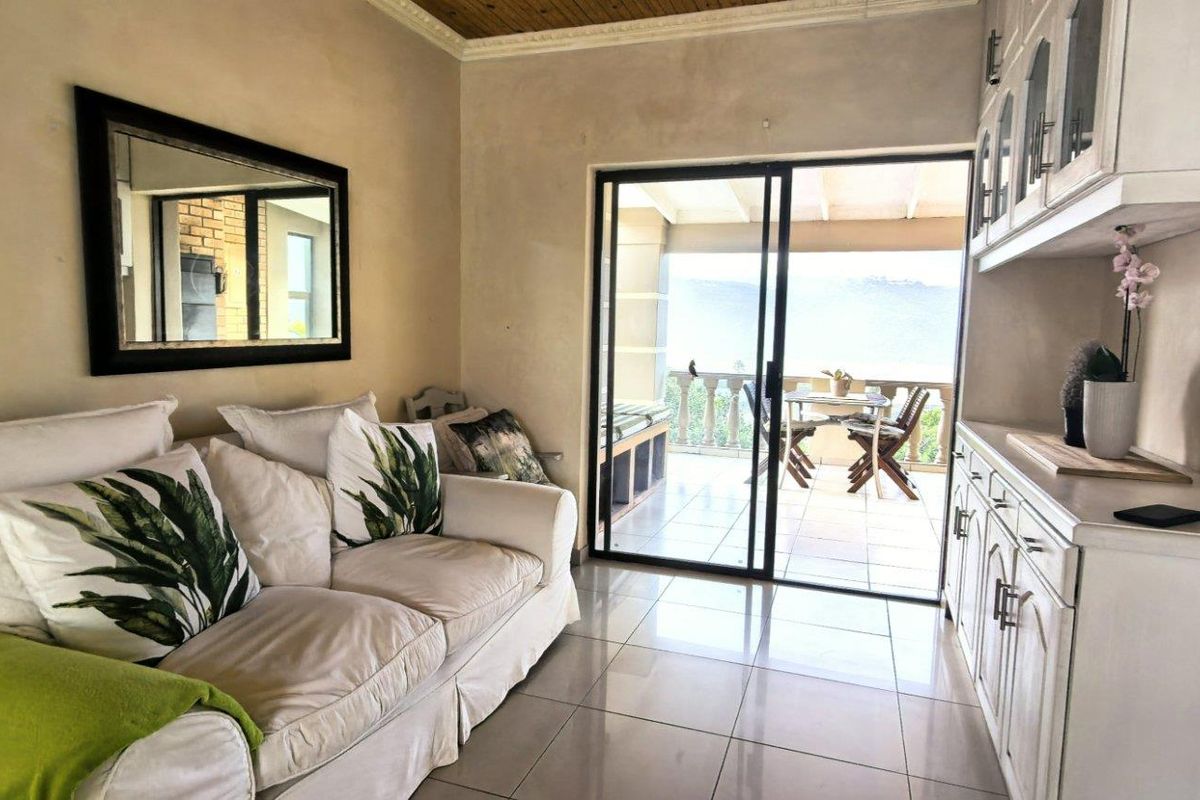 A bright living room featuring tiled floors, built-in cabinetry, and a sliding glass door that opens onto a covered patio with scenic views.