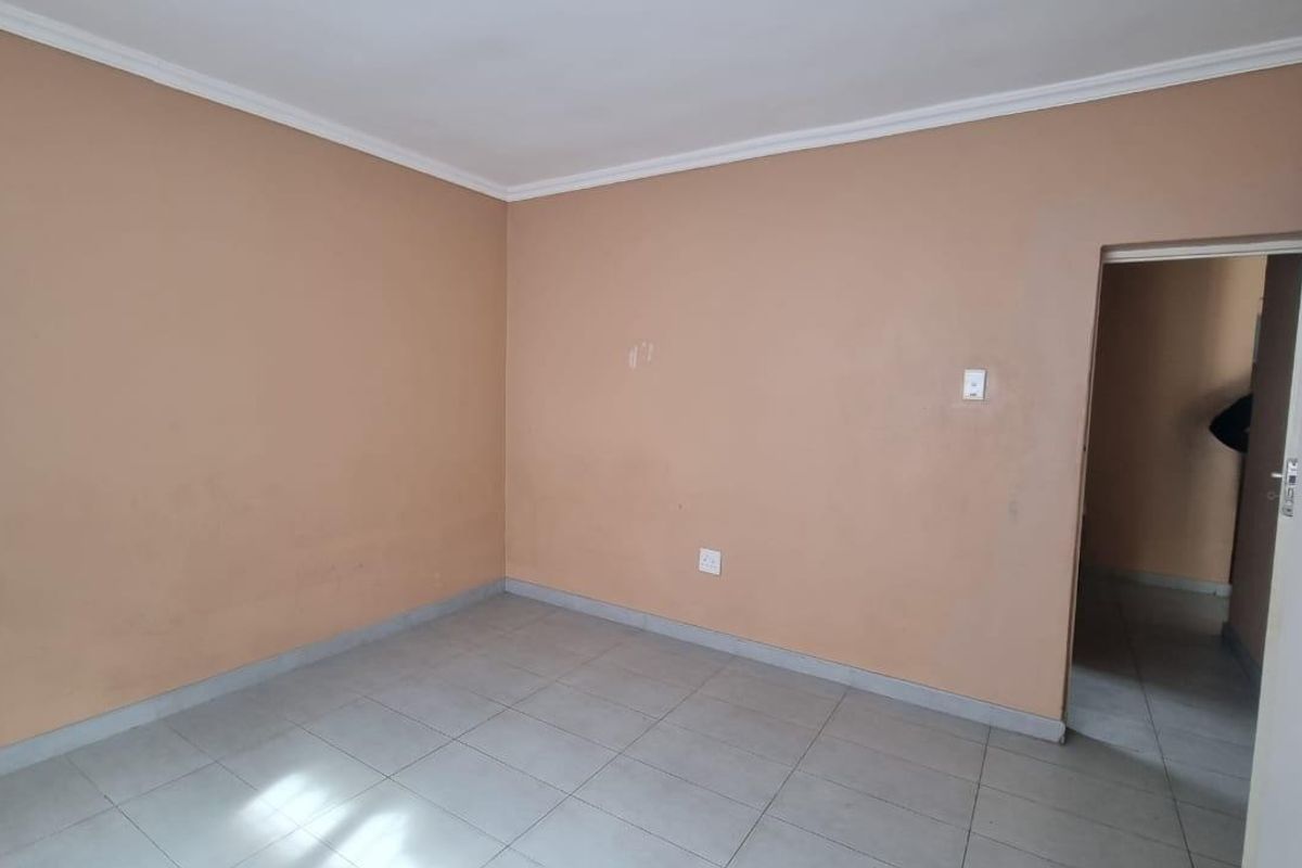 An empty bedroom featuring tiled flooring, built-in wardrobes, and neutral wall finishes, offering a blank canvas for personalization.