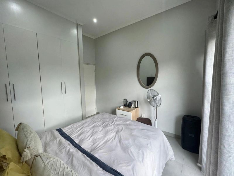 A well-maintained bedroom featuring neutral walls, tiled flooring, and ample built-in cupboard storage space.