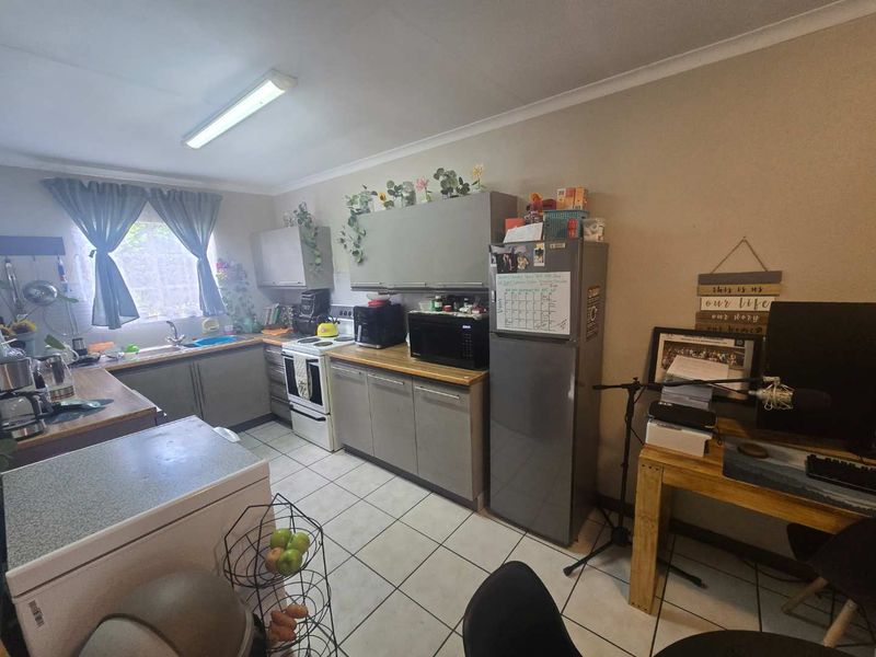 Functional kitchen featuring built-in cabinetry, laminate countertops, and tiled flooring. The space offers a practical layout with a freestanding stove and sink area.