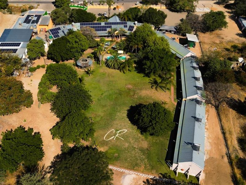 Aerial view of the hotel property featuring multiple buildings with solar panels, a central swimming pool, and landscaped grounds.