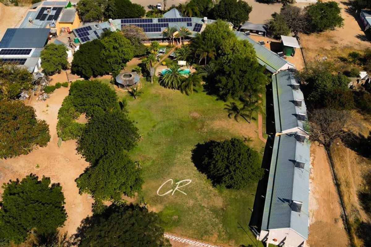 Aerial view of the hotel property featuring multiple buildings with solar panels, a central swimming pool, and landscaped grounds.