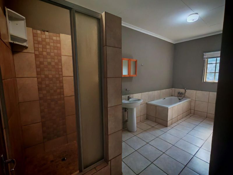 Spacious bathroom featuring a tiled shower enclosure, a built-in bathtub, and a pedestal basin with neutral wall finishes.