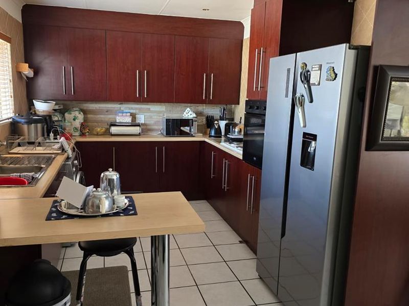 A functional kitchen featuring dark wood-finish cabinetry, tiled flooring, a built-in oven, and a breakfast bar extension.
