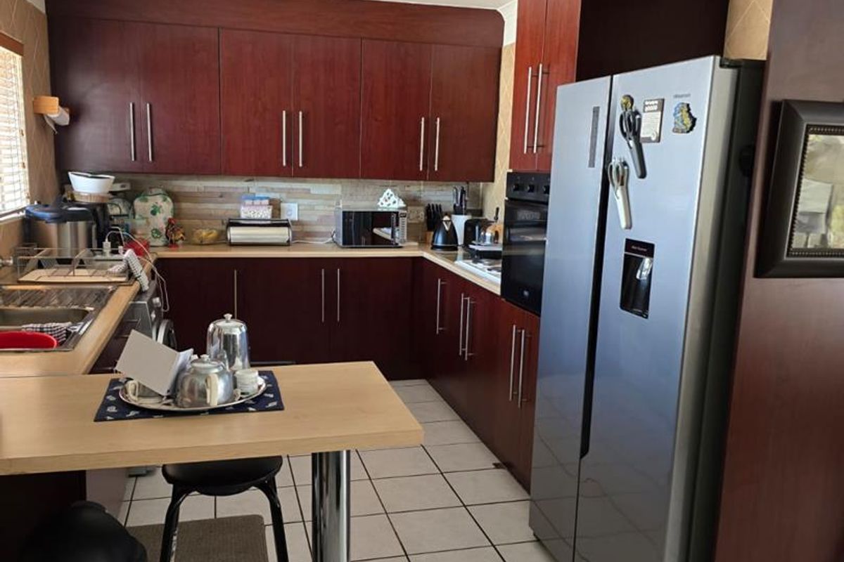 A functional kitchen featuring dark wood-finish cabinetry, tiled flooring, a built-in oven, and a breakfast bar extension.