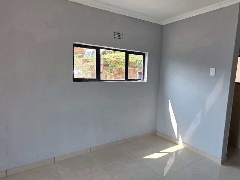 An empty bedroom featuring tiled flooring, a pedestal basin, and an aluminium window frame, awaiting personal touches to complete the space.