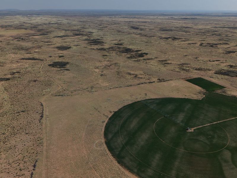 Aerial view of a large farm property featuring a circular irrigated crop field and expansive open grazing land.