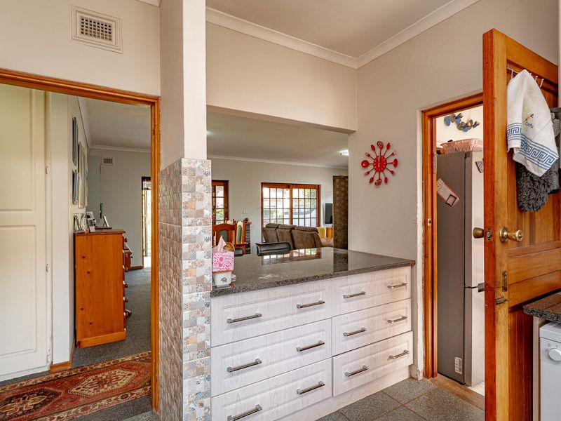 A functional kitchen area featuring granite countertops, modern cabinetry, and tiled flooring, with an open-plan flow leading into the adjacent living space.