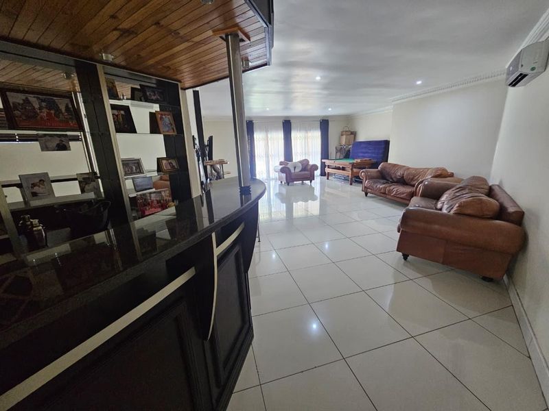Spacious open-plan living area featuring a built-in bar, polished tiled flooring, and integrated air conditioning, offering a versatile layout for entertaining.