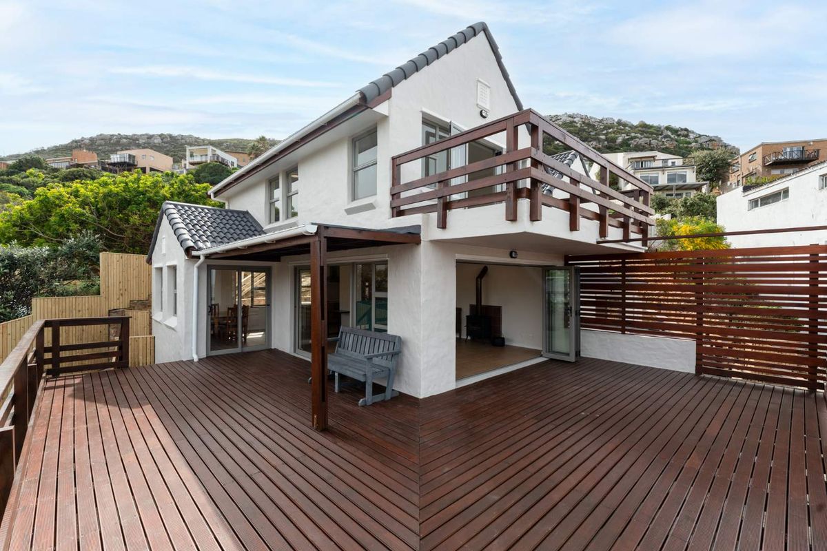 Spacious rear timber deck featuring a covered patio area, upper-level balcony with timber balustrade, and bi-fold doors leading into the home.