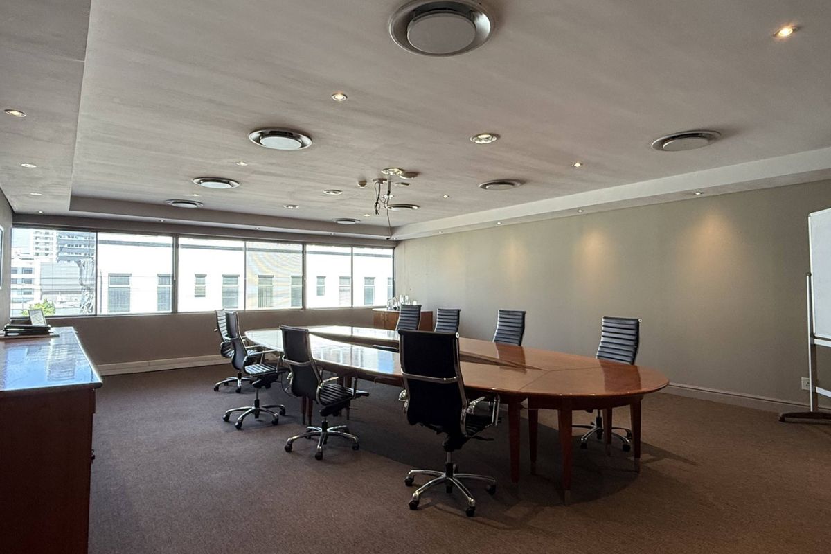 A professional boardroom featuring large windows, recessed ceiling lighting, and built-in cabinetry, providing a functional and well-lit workspace.