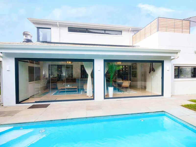 Rear view of the property featuring a swimming pool, paved patio area, and large sliding glass doors providing seamless indoor-outdoor flow.