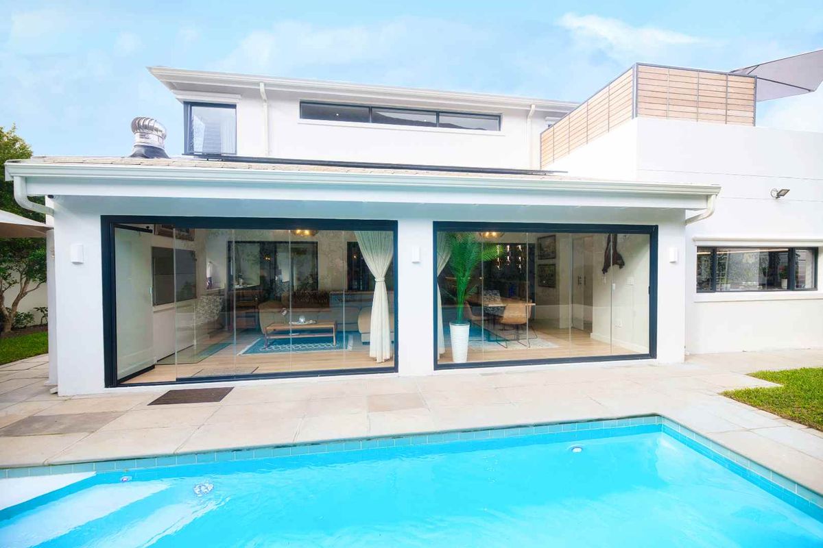 Rear view of the property featuring a swimming pool, paved patio area, and large sliding glass doors providing seamless indoor-outdoor flow.