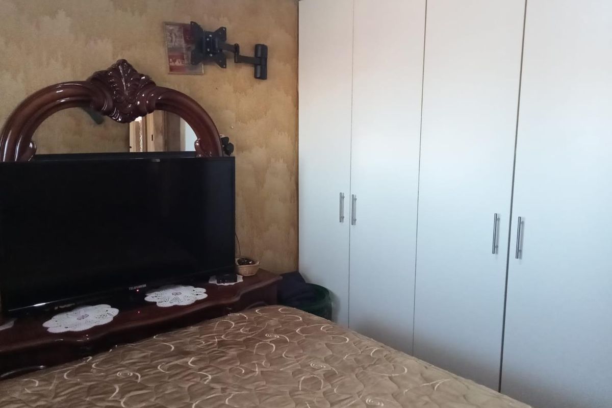 A bedroom featuring a large white built-in wardrobe with modern handles and decorative coving along the ceiling.