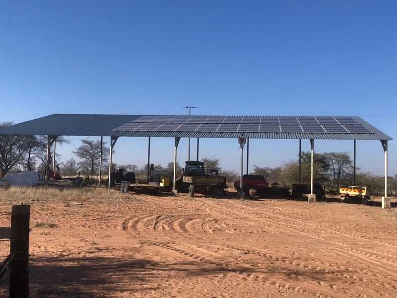 A large open-sided farm utility structure featuring a corrugated metal roof equipped with a solar panel array for sustainable energy generation.